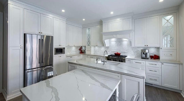 White shaker kitchen featuring Calacatta Ultra quartz waterfall island, Arabescato Venato marble subway tile backsplash, floor-to-ceiling cabinets, and Jeffrey Alexander hardware