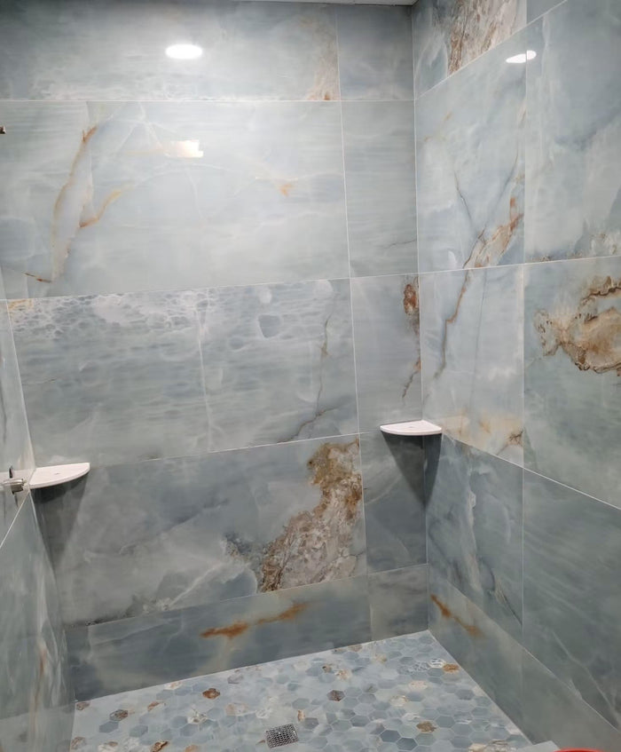 Blue large-format tile shower with coordinated hexagon mosaic floor and visible grout-line layout.