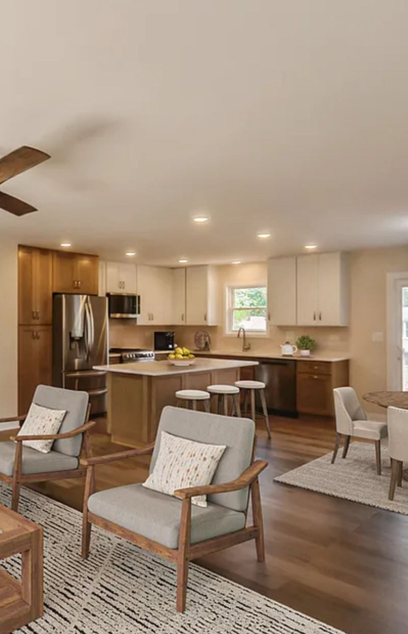 Open concept living and kitchen with white upper cabinets, warm wood lower cabinets and island, quartz countertop, stainless steel appliances, and hardwood floors