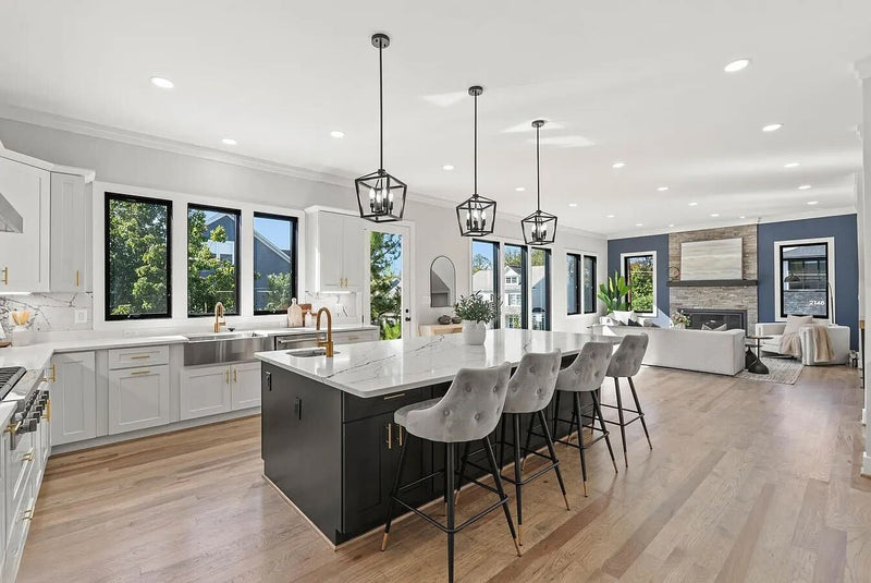 1:30 PM
Open concept kitchen with light gray shaker cabinets, black island, white marble quartz countertop, gold hardware and faucet, black lantern pendants, farmhouse sink, and light hardwood floors