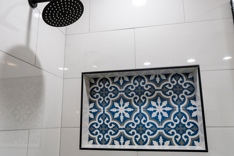 Blue and white encaustic patterned tile shower niche with large format white wall tile and black rain shower head