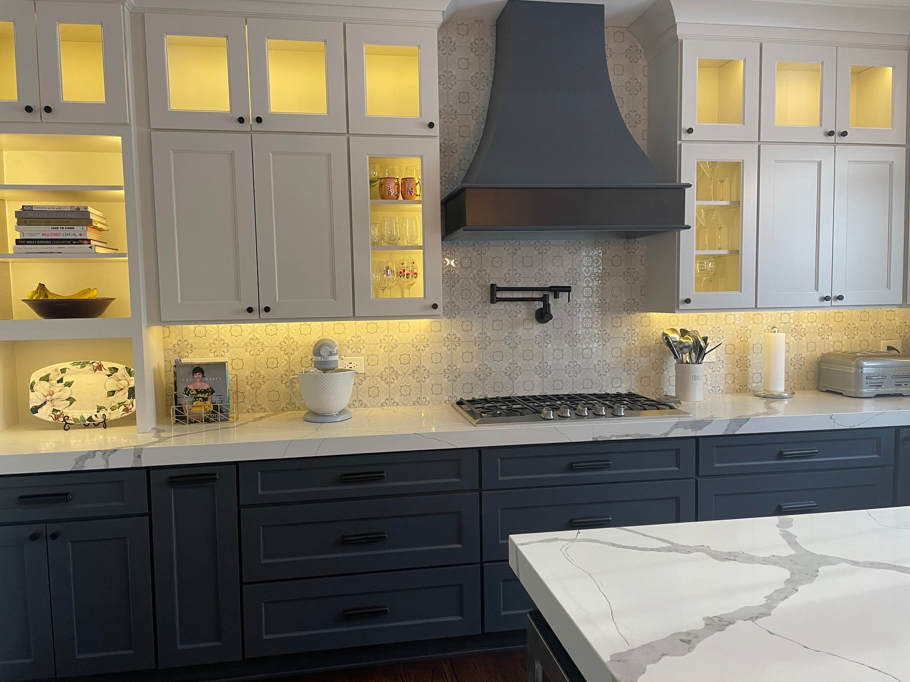 Custom kitchen featuring Woodland cabinetry, mitered quartz countertops, statement wood hood, integrated cabinet lighting, and premium finishes.
