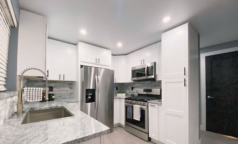 White shaker kitchen cabinets with marble countertops and stainless steel appliances