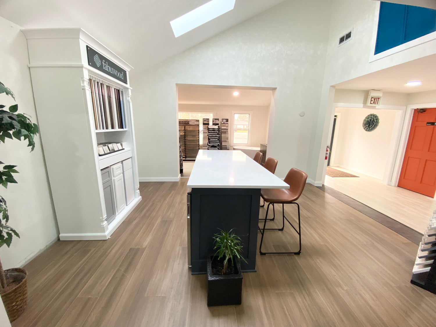 Modern showroom interior with a long white table and chairs in a well-lit room.