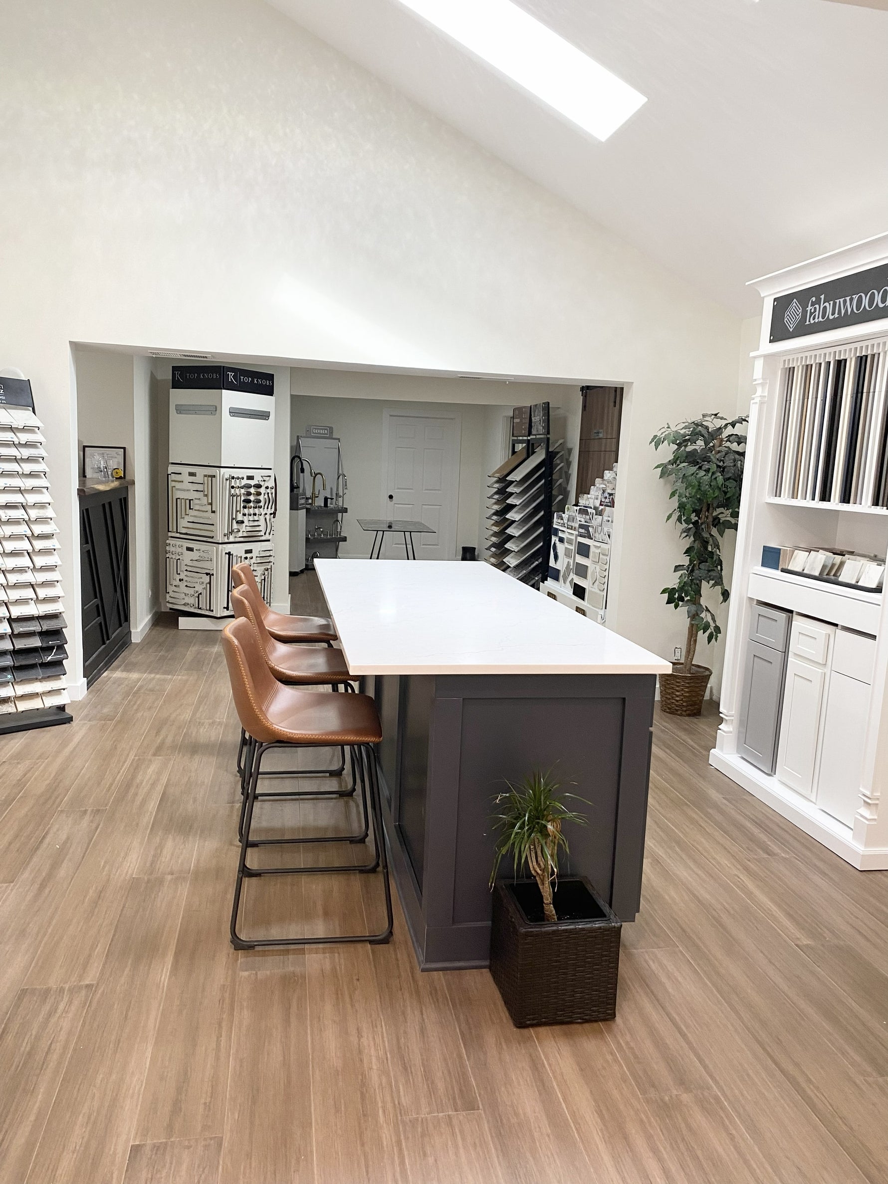 Showroom interior with cabinet displays, tile and flooring samples, hardware boards, and design consultation island