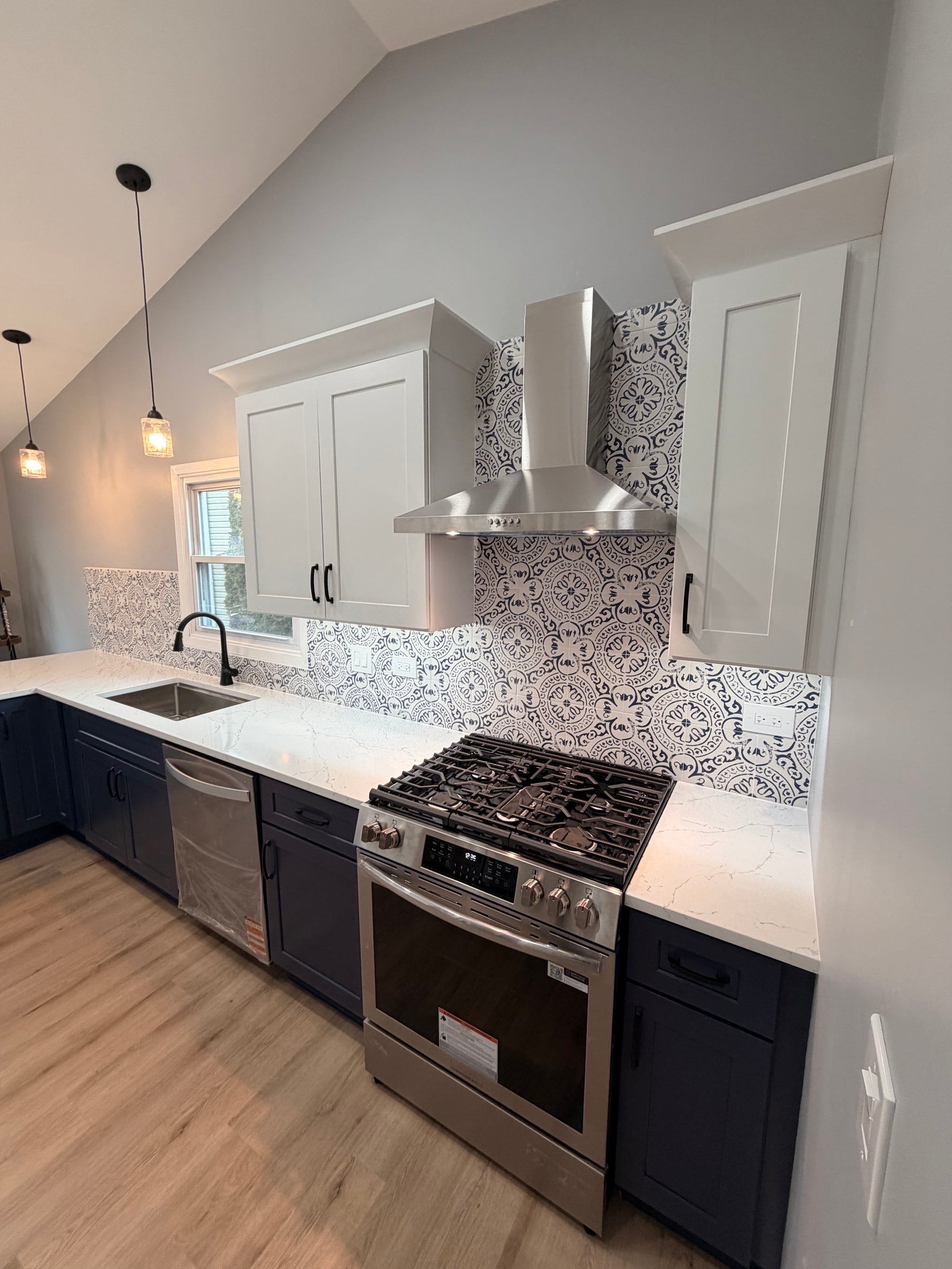 Rose Hill Cabinets paired with MSI patterned tile backsplash, quartz countertops, black Innovations Lighting pendants, and Top Knobs hardware in a modern navy and white kitchen design