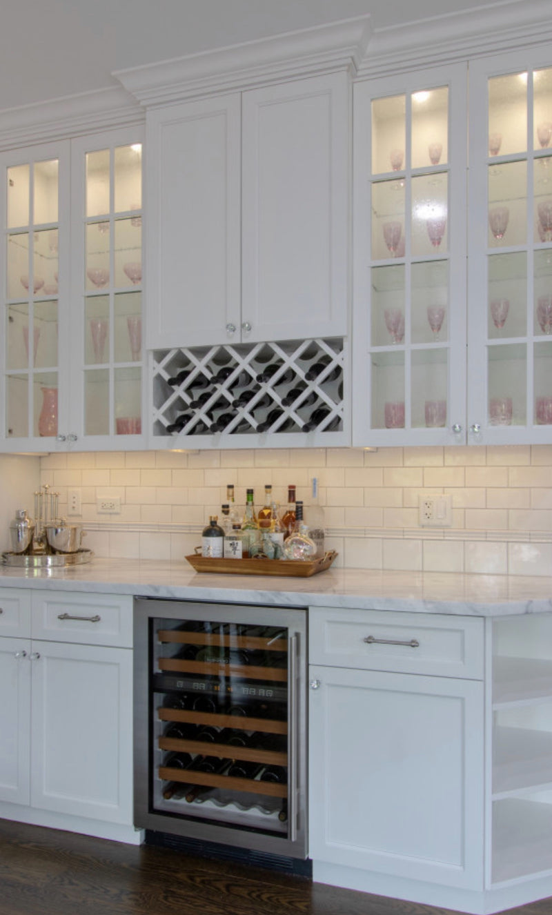 1:23 PM
White shaker butler's pantry with lit glass-front upper cabinets, built-in wine rack, undercounter wine refrigerator, marble countertop, subway tile backsplash, and brushed nickel hardware