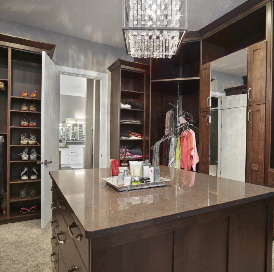 Custom dark walnut walk-in closet cabinet collection with center island, shoe shelving and crystal chandelier