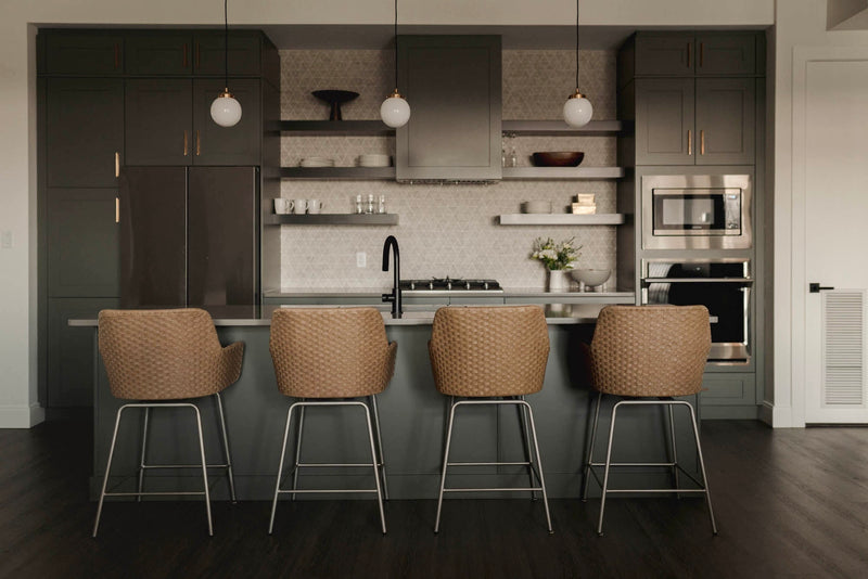 Grey shaker kitchen cabinets with brass hardware, open shelving, geometric tile backsplash, and rattan bar stools at kitchen island