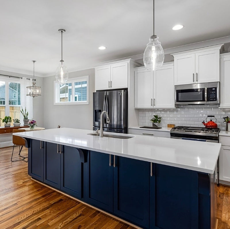 11:28 AM
Two-tone kitchen with white shaker upper cabinets, navy blue island, white quartz countertop, subway tile backsplash, and hardwood floors