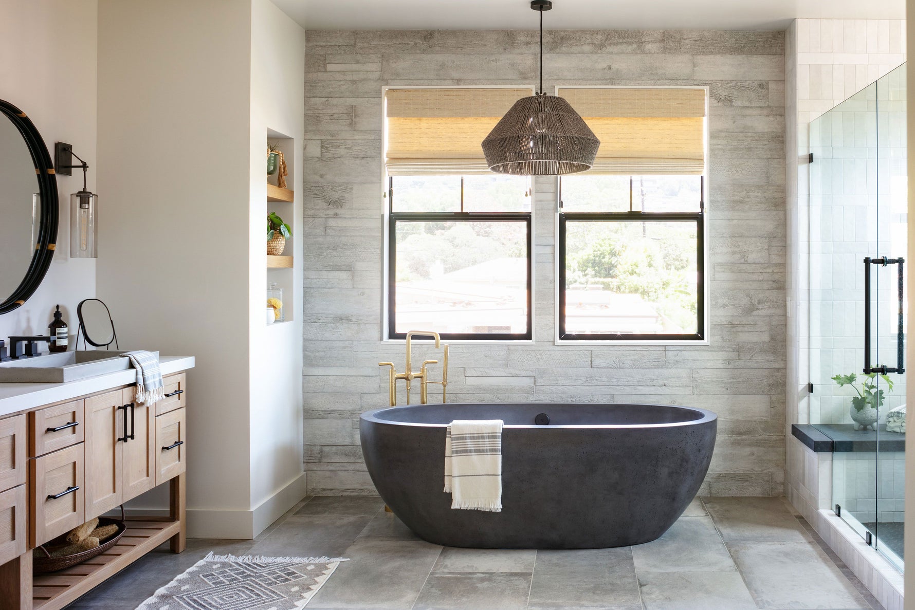 Natural wood bathroom vanity with black freestanding soaking tub and wood look wall tile