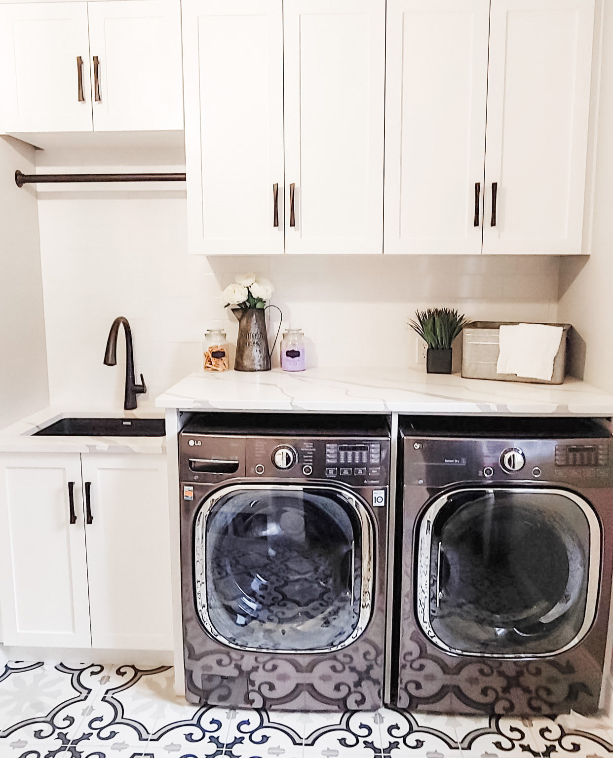 Finished laundry room with Rose Hill white shaker cabinets, MSI patterned tile flooring, quartz countertop, and front-loading washer and dryer in a functional, design-forward space