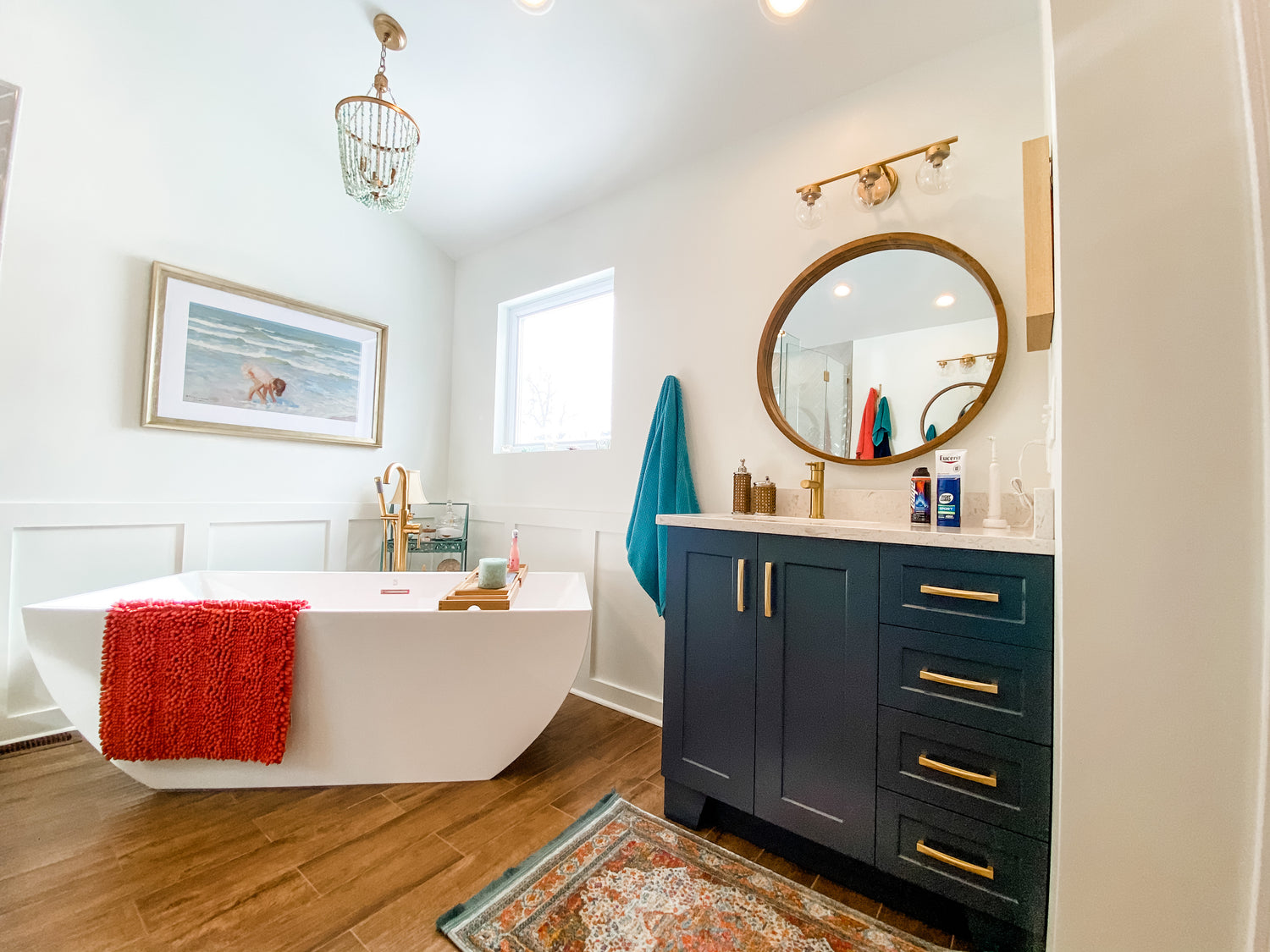 Navy bathroom vanity with quartz countertop and brass hardware, paired with a freestanding soaking tub and statement vanity and accent lighting, highlighting premium bathroom furniture, fixtures, and lighting finishes