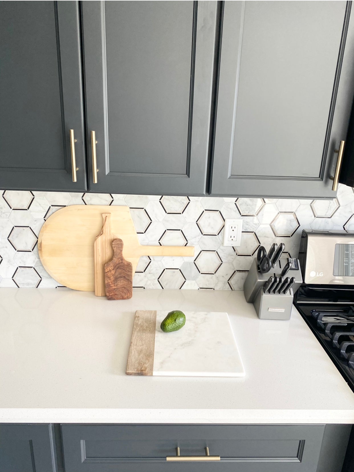 Rose Hill gray shaker kitchen cabinets paired with Emser geometric tile backsplash, quartz countertop, and brass cabinet hardware.