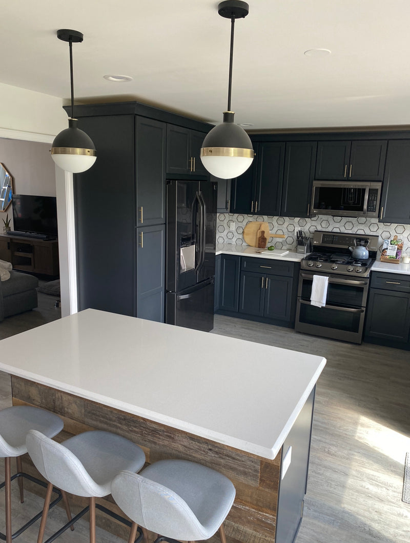 Kitchen island with wood panel detailing, dark cabinetry, quartz countertop, and LVT flooring, showcasing durable flooring, custom island finishes, and modern kitchen materials
