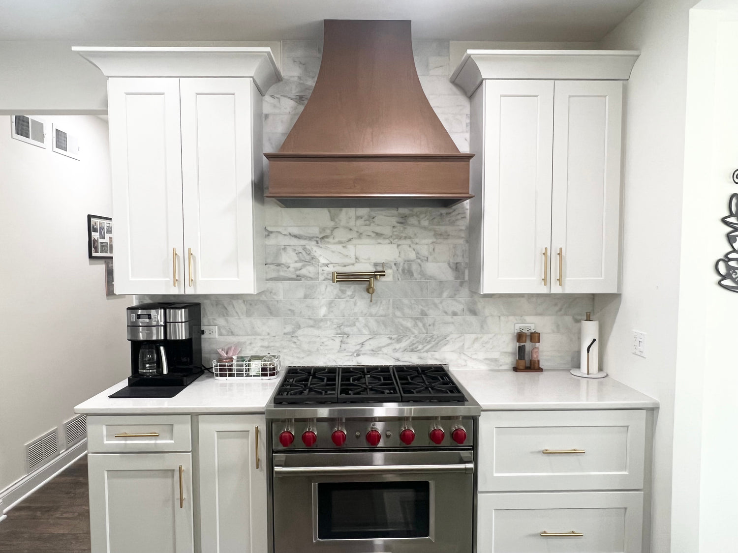 White shaker cabinet kitchen remodel with copper range hood, marble backsplash, and professional gas range