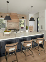 Modern kitchen island featuring pendant lighting, quartz countertops, wood range hood, and integrated sink fixtures, highlighting layered lighting and high-end kitchen finishes