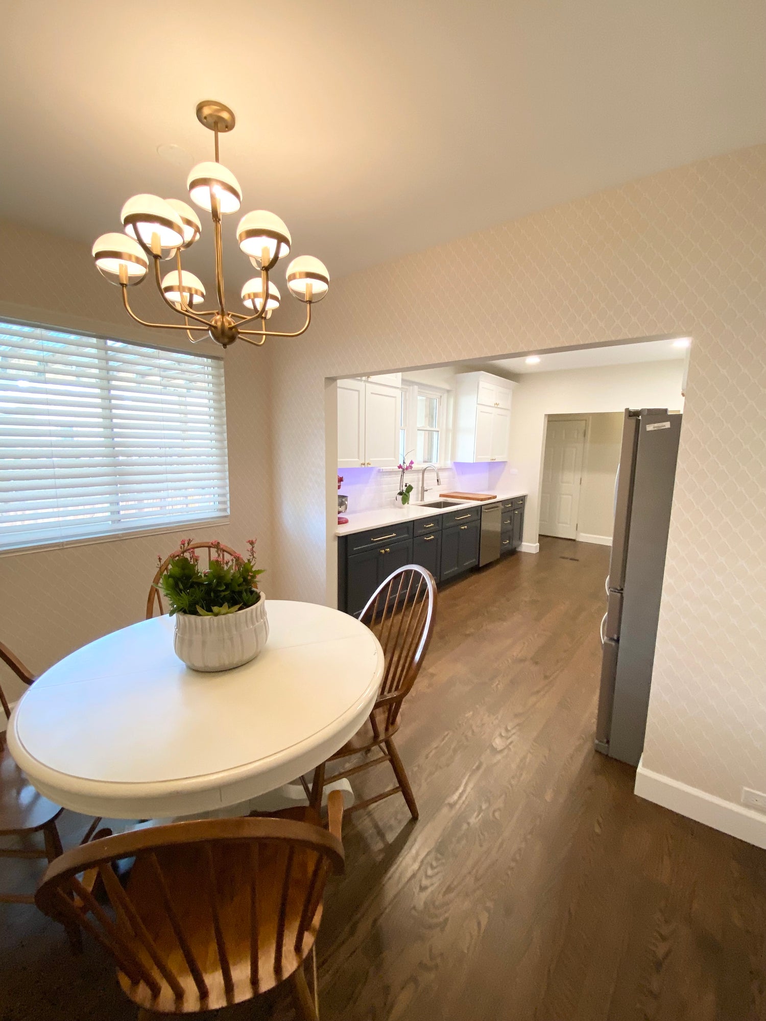 Dining area featuring engineered hardwood flooring, Savoy decorative lighting fixture, open-concept layout, and warm modern finishes.