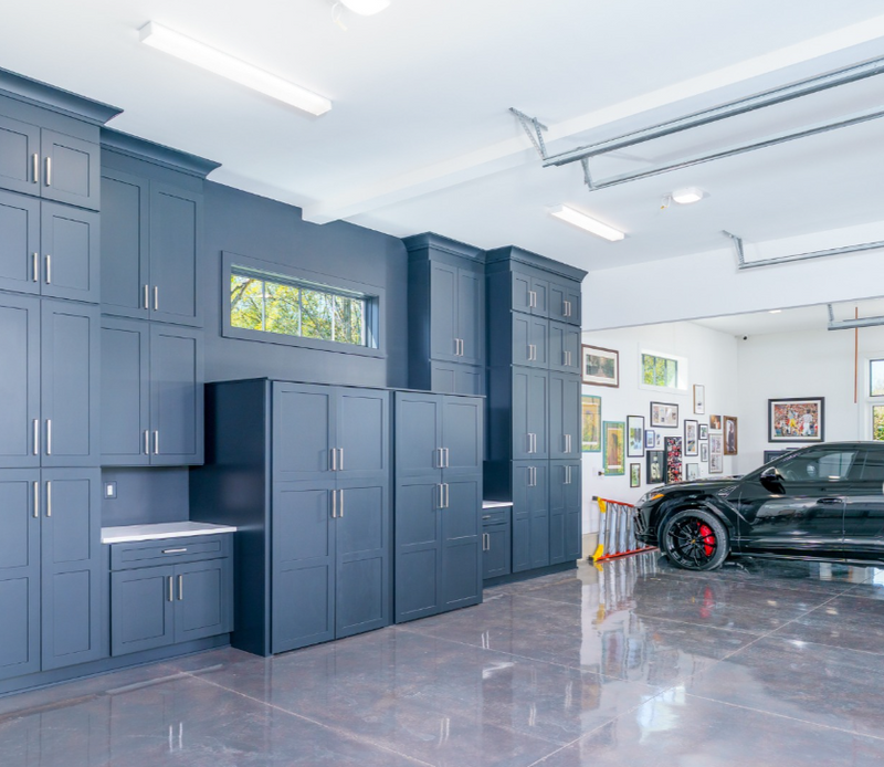 Floor-to-ceiling navy blue shaker cabinets with crown molding in a luxury garage storage installation