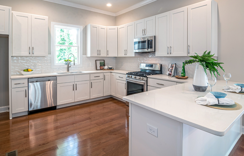 White shaker kitchen cabinets with white quartz countertops, glass subway tile backsplash, and dark hardwood floors