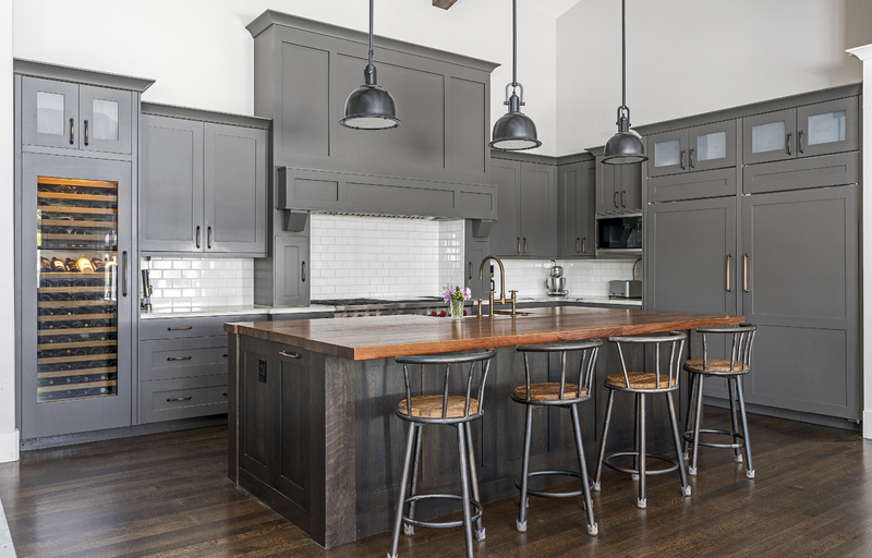Gray shaker kitchen cabinets with butcher block island, built-in wine fridge, white subway tile backsplash, and industrial pendant lighting