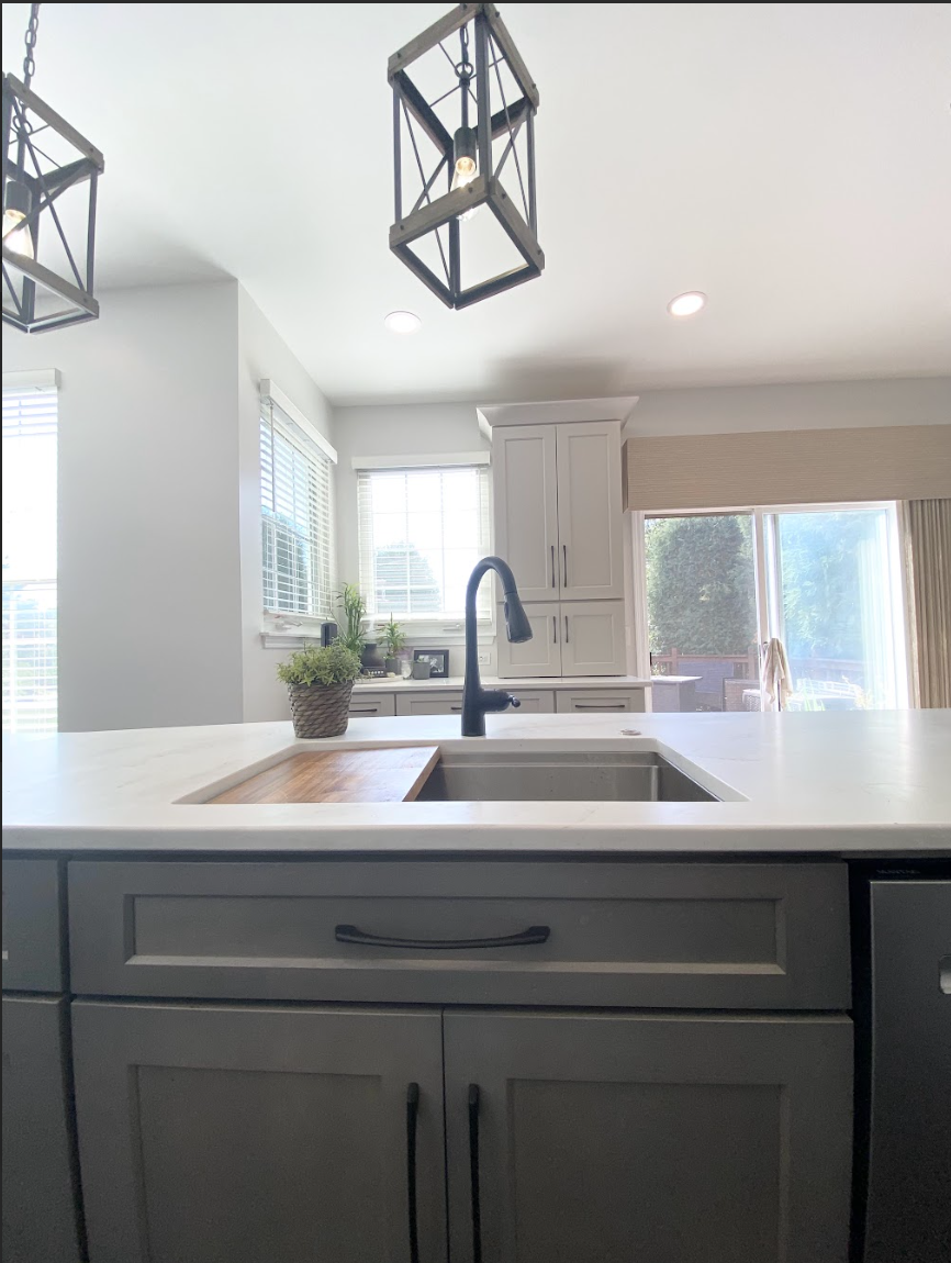 Open concept kitchen remodel with gray island, white shaker cabinets, gray shaker cabinets, black pendant lighting and quartz countertops
