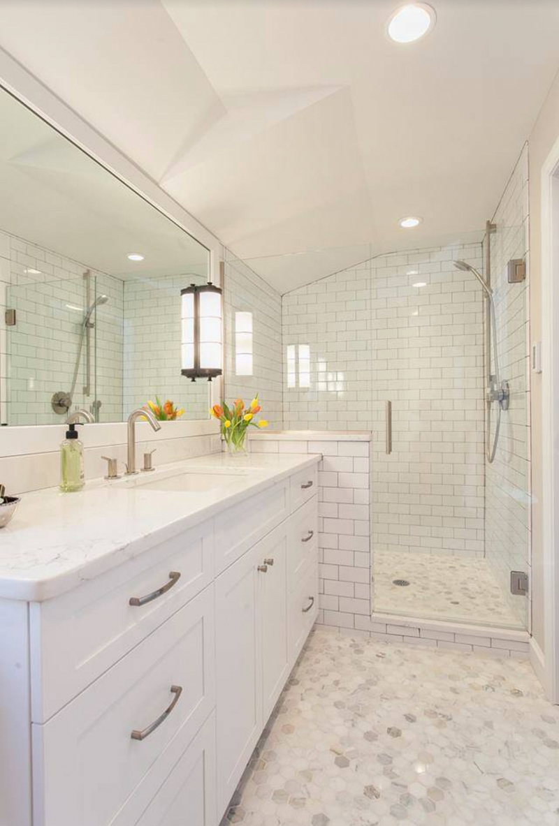 White shaker bathroom vanity with marble countertop, subway tile shower, and hexagon marble floor tile