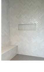 Bathroom and shower white glossy tile in a herringbone design with a nook niche and custom shower bench curated by Emerald Fern Finishes, featuring moisture-resistant tile from Emser for long-term durability.