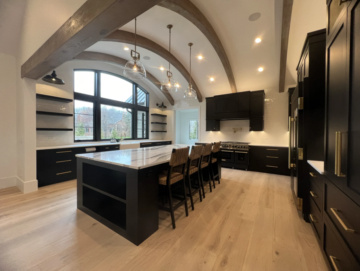 Hardwood Bruce flooring installed in a custom kitchen renovation with Woodland black shaker cabinets purchased by Emerald Fern Finishes, showcasing timeless natural wood flooring.