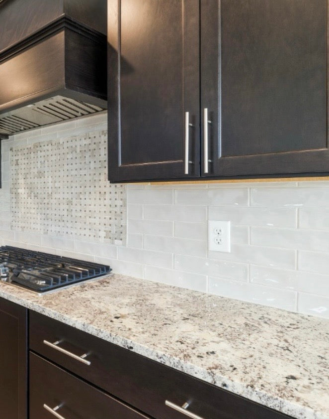 Dark espresso shaker cabinets with granite countertop, white subway tile backsplash, decorative mosaic tile accent, and brushed nickel hardware