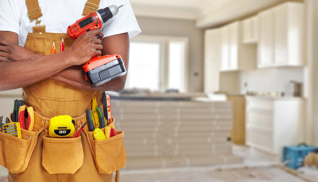 Home renovation trade professional holding a drill in a kitchen under construction
