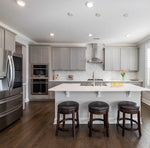 Modern kitchen with stainless steel appliances, white island, gray shaker rose hill cabinets and wooden flooring.