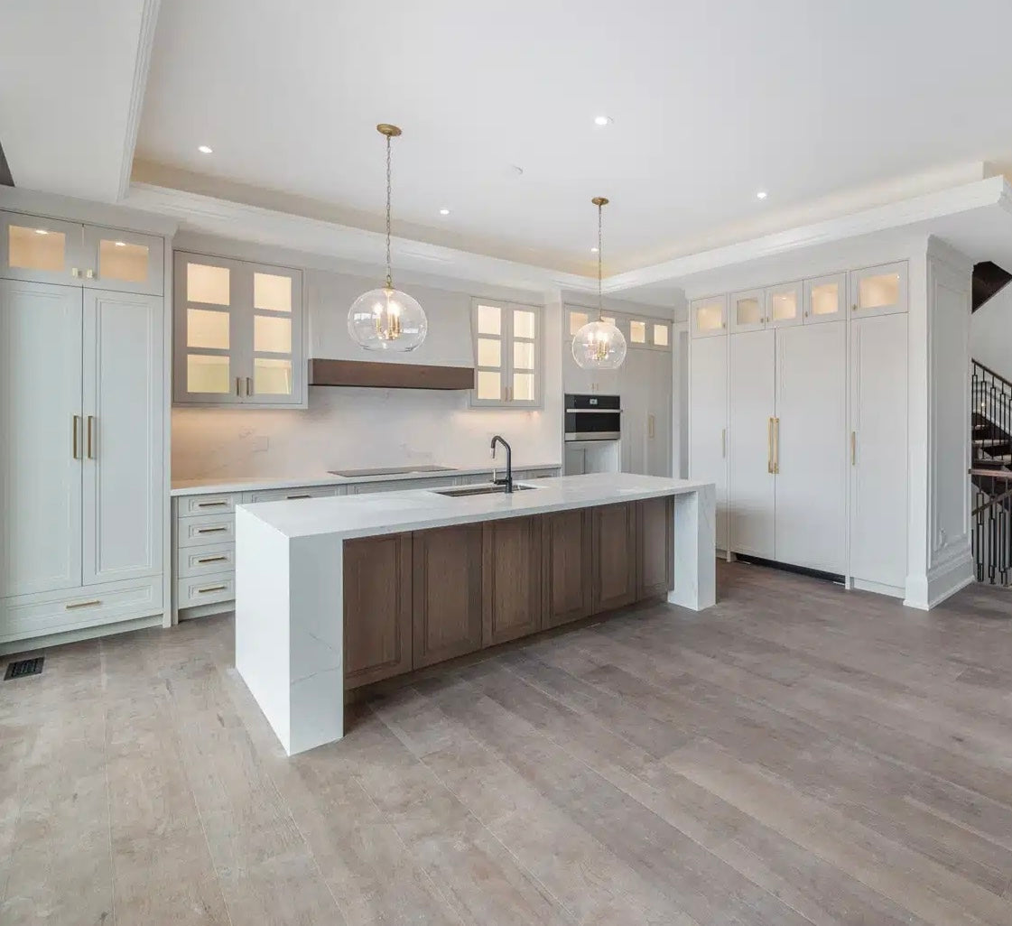 Modern kitchen featuring LVT flooring, white shaker cabinets, a wood island, and glass pendant lighting in a bright open layout.