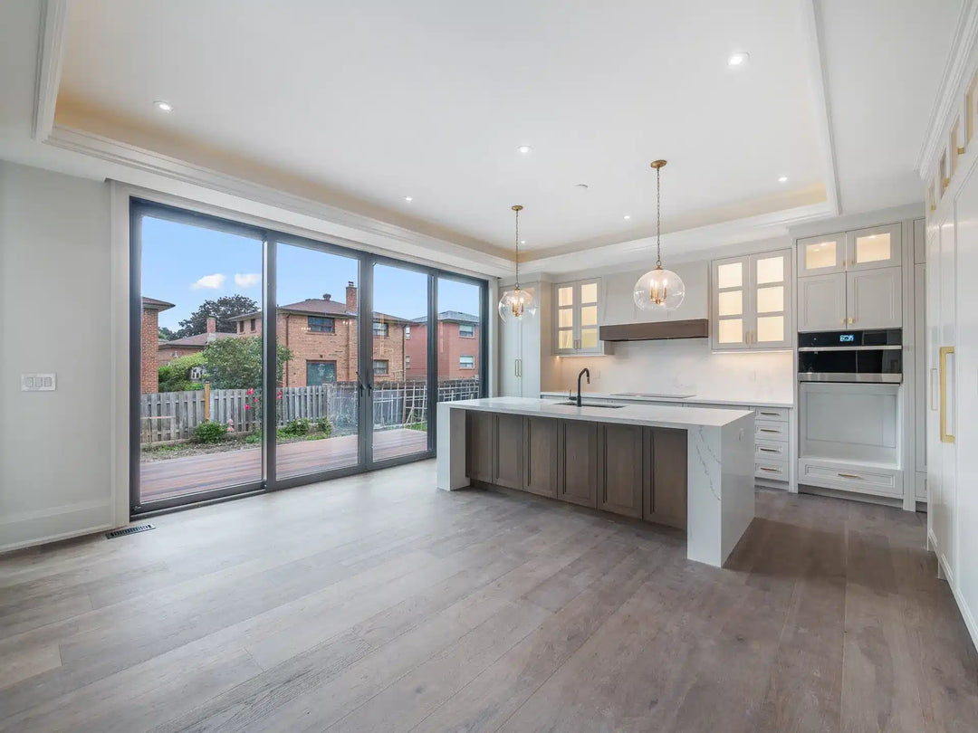 Open-concept kitchen with wide plank LVT flooring, white cabinetry, a wood island, and glass pendant lighting.