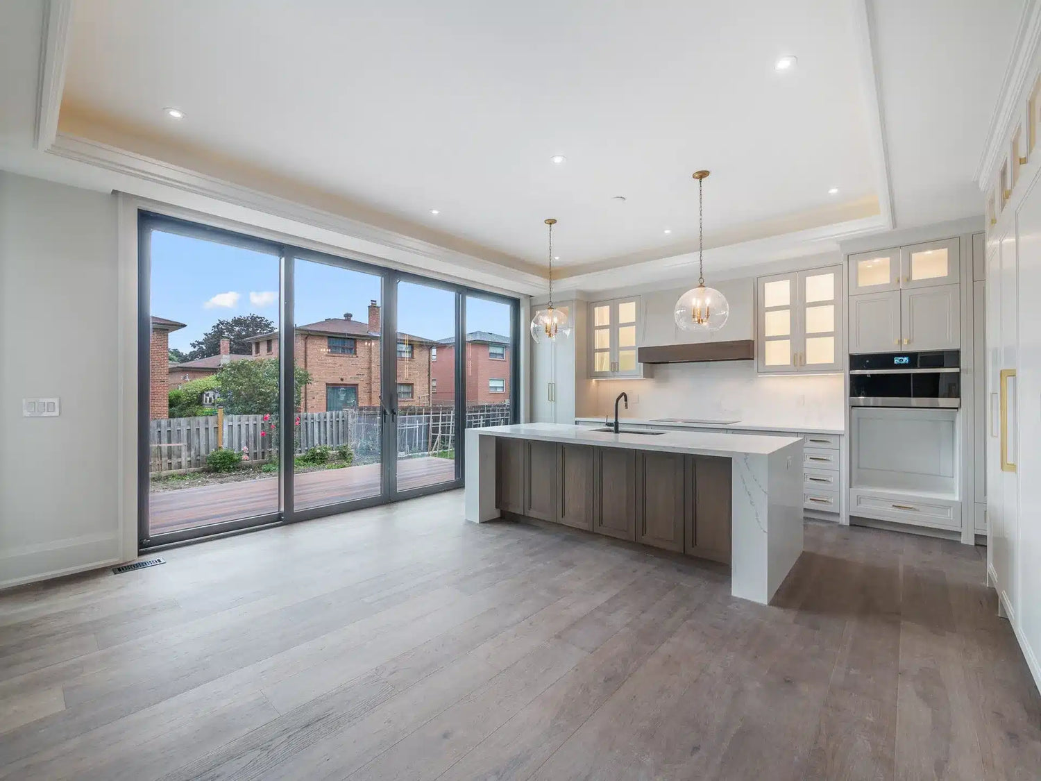 Open-concept kitchen with wide plank LVT flooring, white cabinetry, a wood island, and glass pendant lighting.