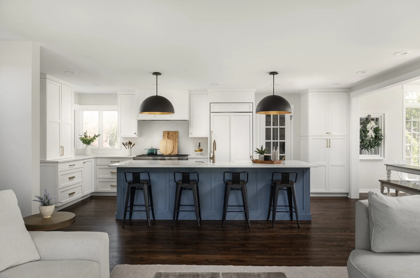 Modern kitchen remodel with white shaker cabinets, marble herringbone backsplash, pendant lighting, and blue custom island with hardwood floors throughout open space - complete kitchen package from Emerald Fern Finishes
