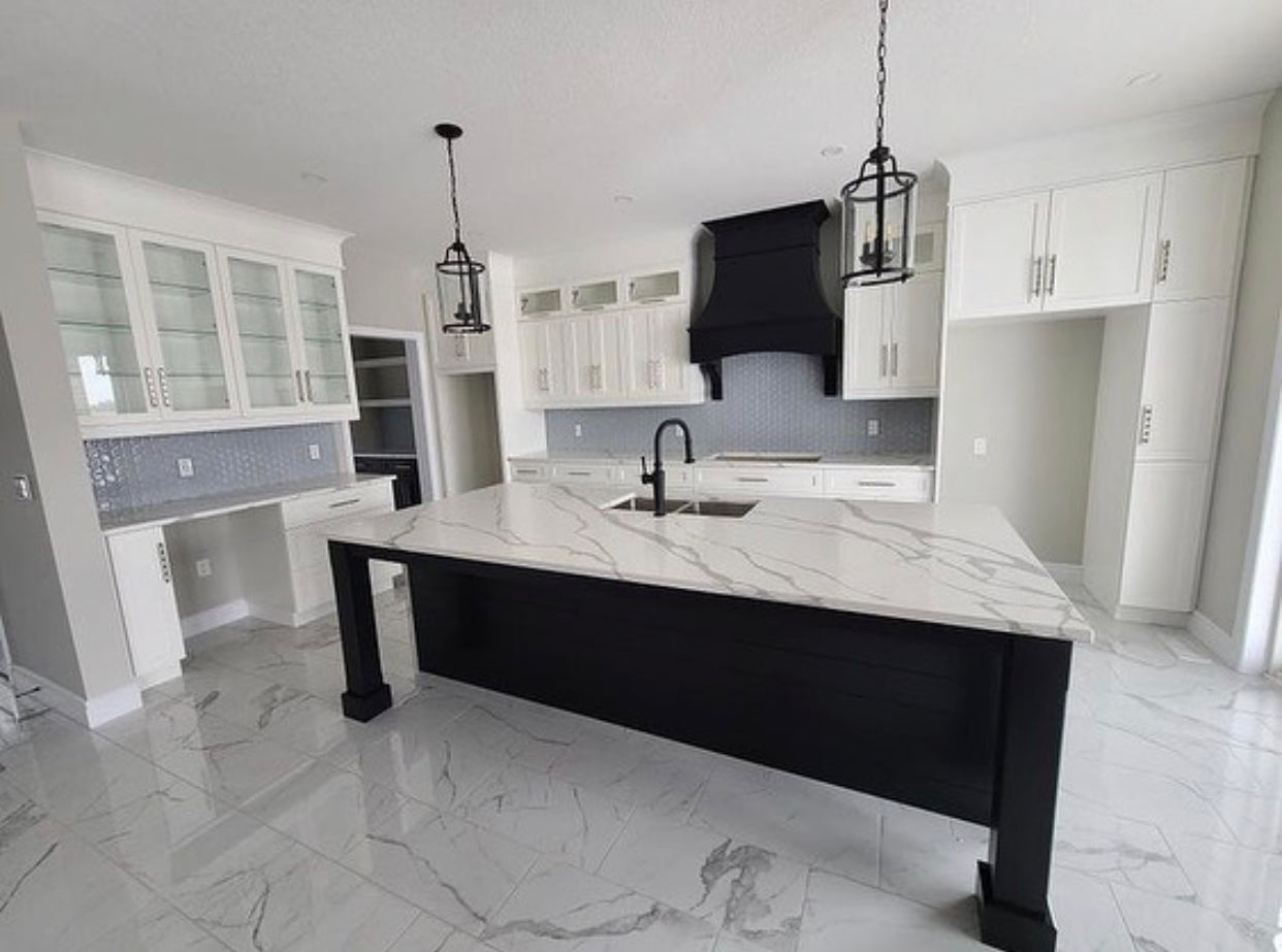 White shaker kitchen with custom black wood hood and custom island, quartz countertops, and Decovita porcelain floor tile, blending Rose Hill Cabinets with bespoke millwork elements, MSI floor tile, Ruvatti workstation sink, Top Knobs cabinet hardware bundle purchase from Emerald Fern Finishes.