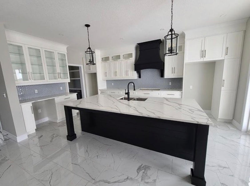 White shaker kitchen with custom black wood hood and custom island, quartz countertops, and Decovita porcelain floor tile, blending Rose Hill Cabinets with bespoke millwork elements, MSI floor tile, Ruvatti workstation sink, Top Knobs cabinet hardware bundle purchase from Emerald Fern Finishes.