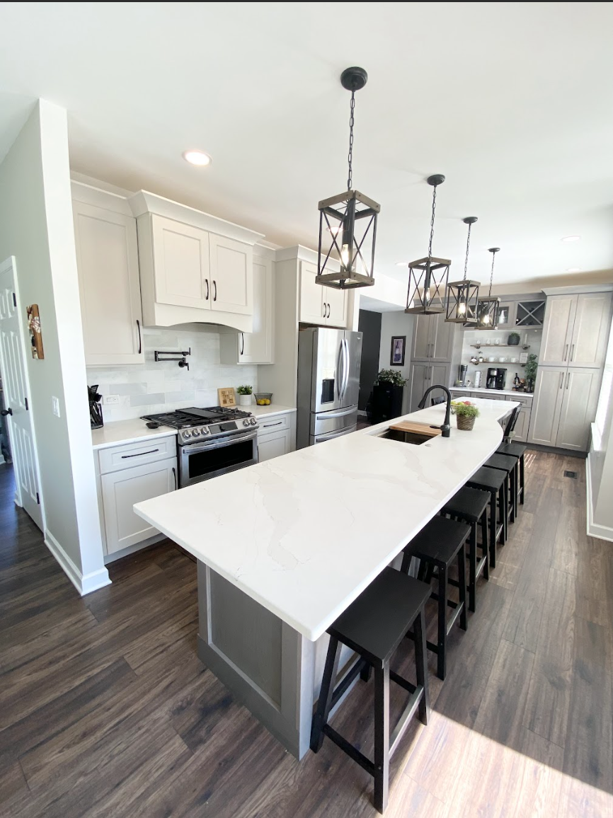 White shaker kitchen remodel with quartz waterfall island, black bar stools, industrial pendant lighting, and dark hardwood floors — complete kitchen package from Emerald Fern Finishes